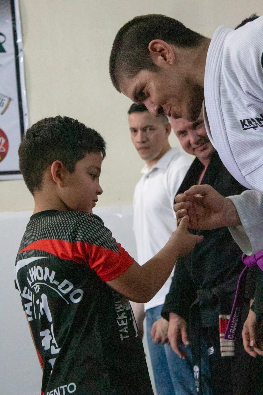 Instructor de A J Contact entregando el cinturón a un alumno